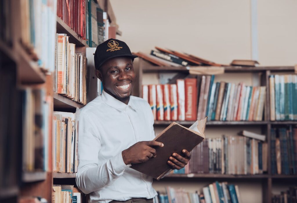 pexels-photo-31245739 A joyful man reading in a Ghanaian library, symbolizing education and knowledge.