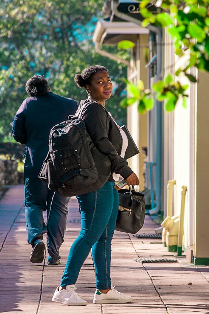 Young African woman walking outdoors in Lobamba, Eswatini, wearing casual attire.